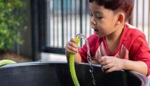 Foto de garotinho consumindo água direto da mangueira