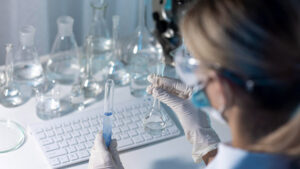 Mulher cientista realizando análise de água em laboratório, com utilização de EPIs